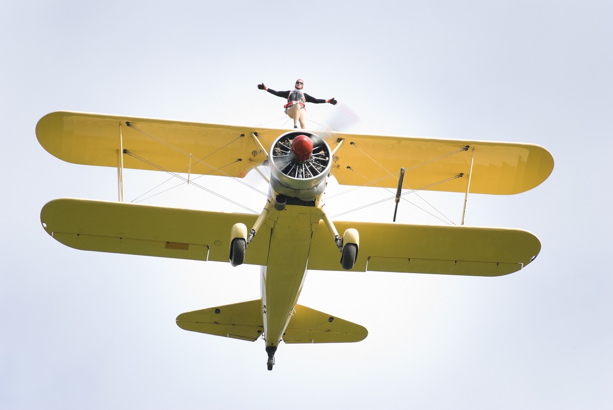 woman flying on top of two bi-plane
