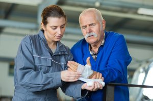 A Woman attends to a male colleague who has been injured in a factory accident