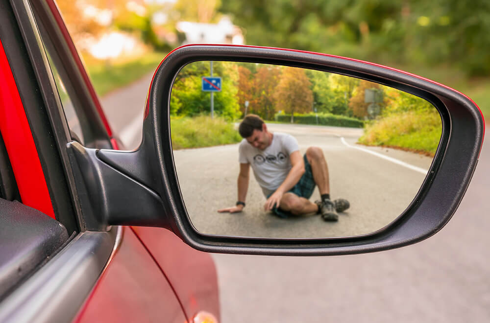 An injured pedestrian is visible a car's wing mirror