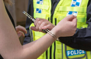 Police officer putting handcuffs on detainee