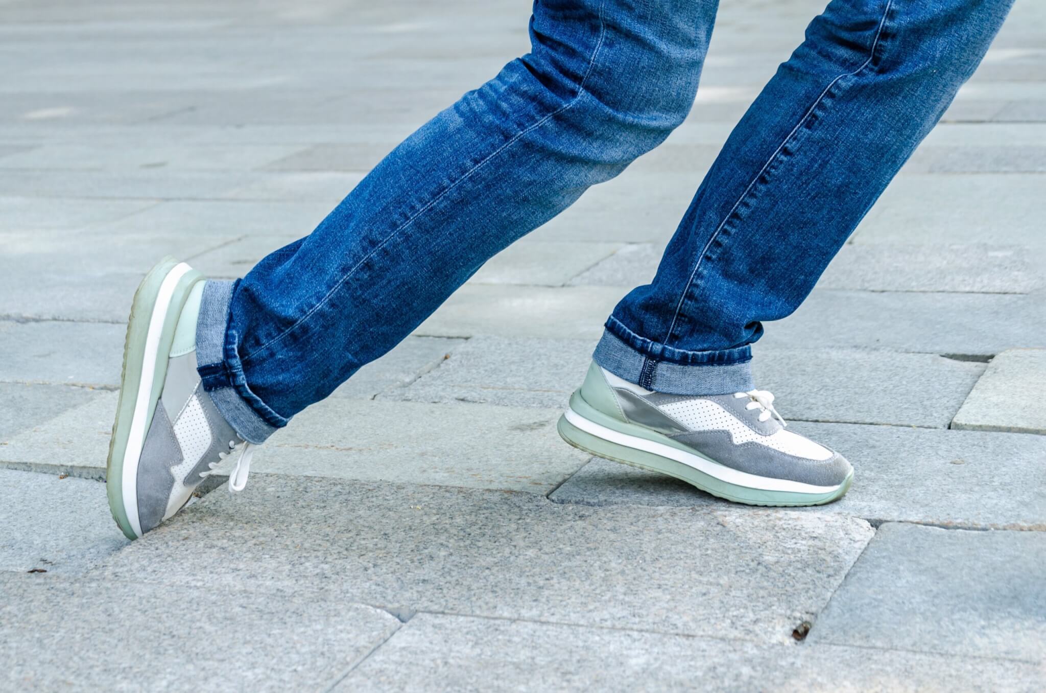 Close up of woman tripping on uneven paving stone.